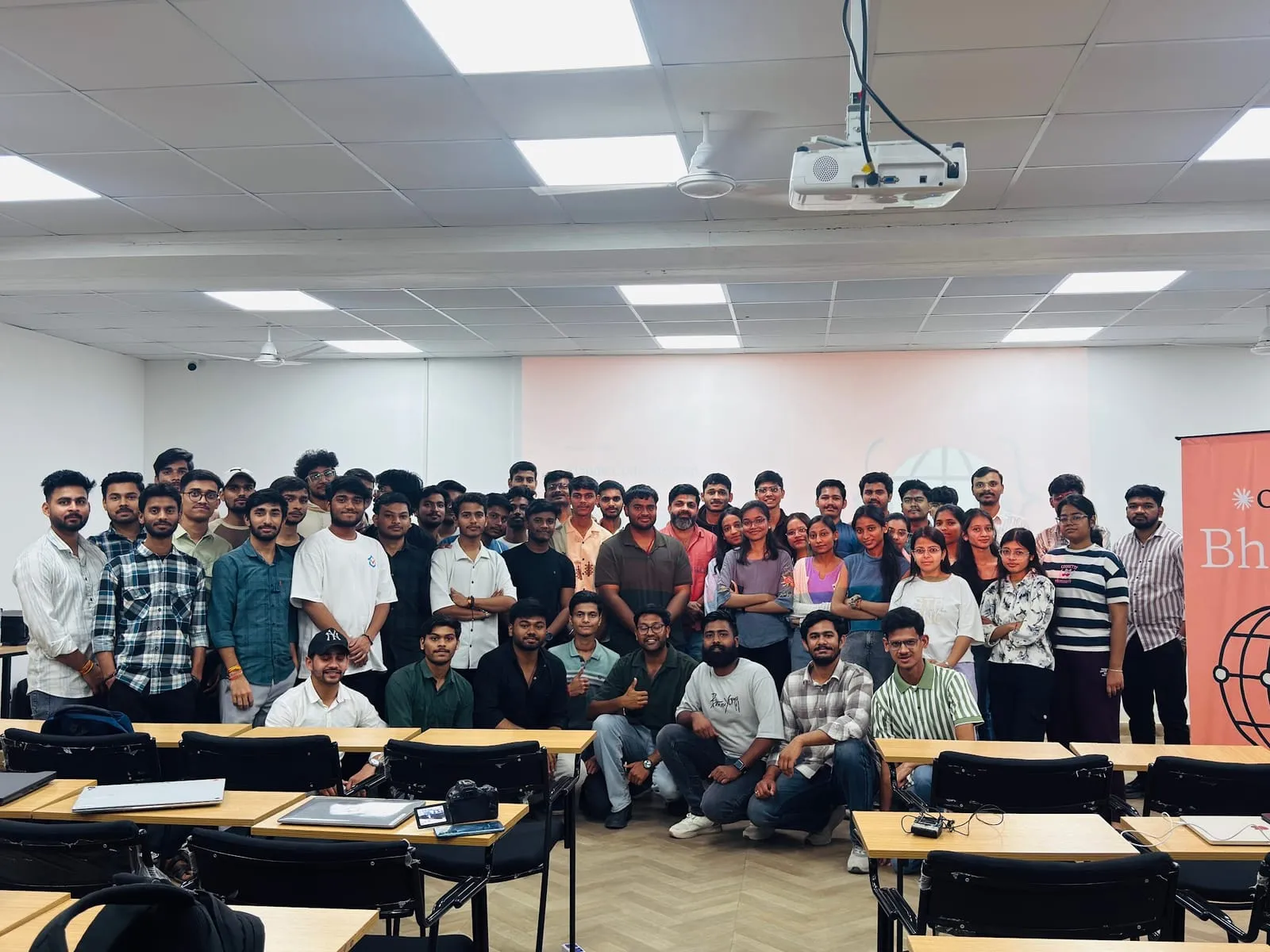 Attendees of Claude Code for Builders standing behind the classroom desks for a group photo, with the Claude Bhopal banner at the right
