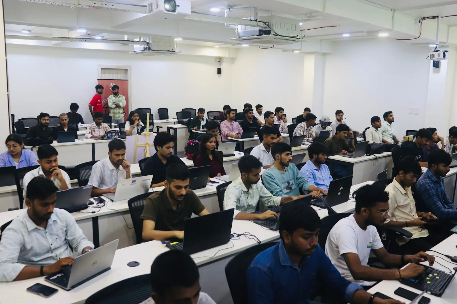 Participants working on laptops along the rows of desks in the lab classroom