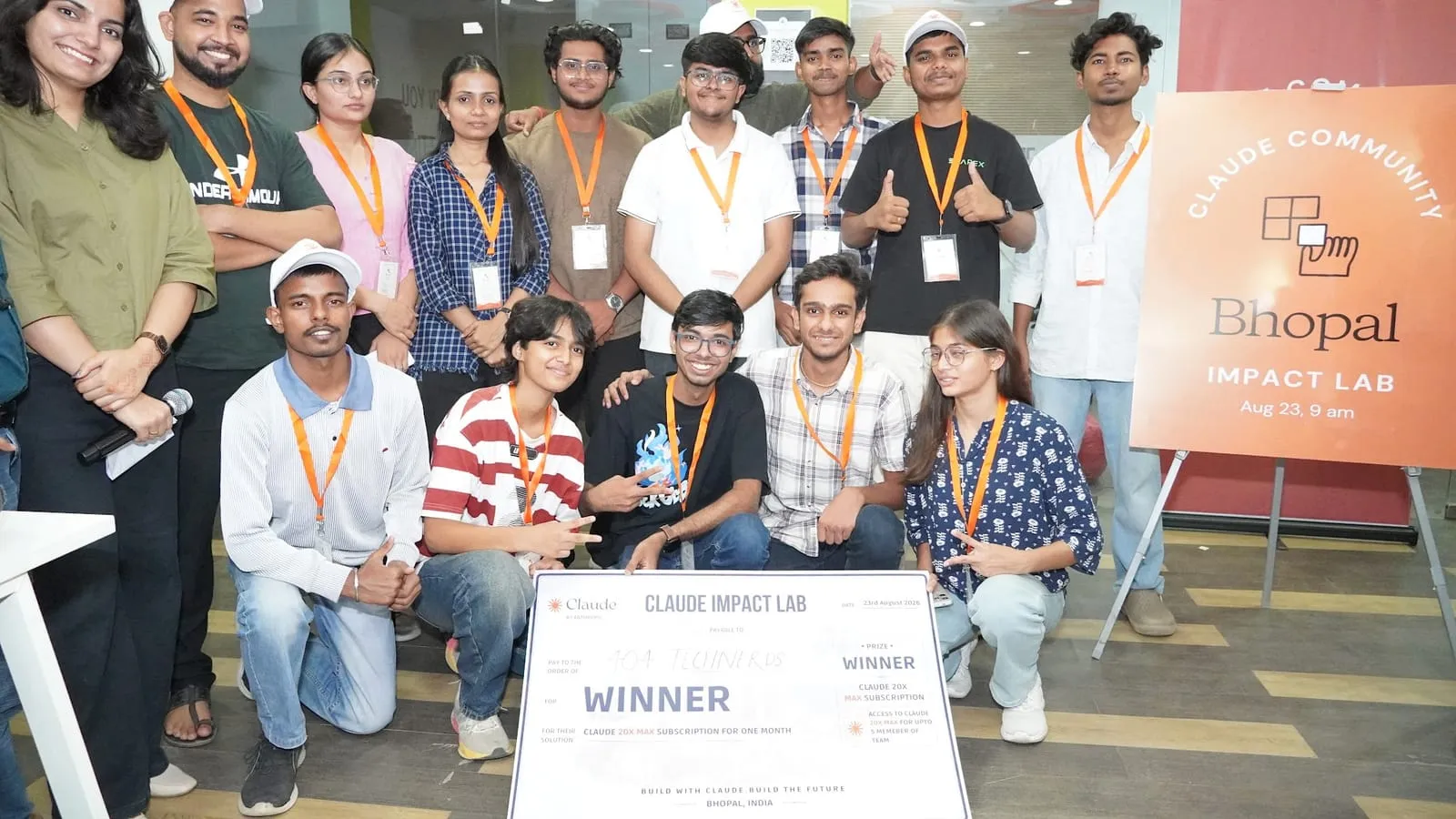 The winning team posing with the Winner cheque beside the Claude Community Bhopal Impact Lab board