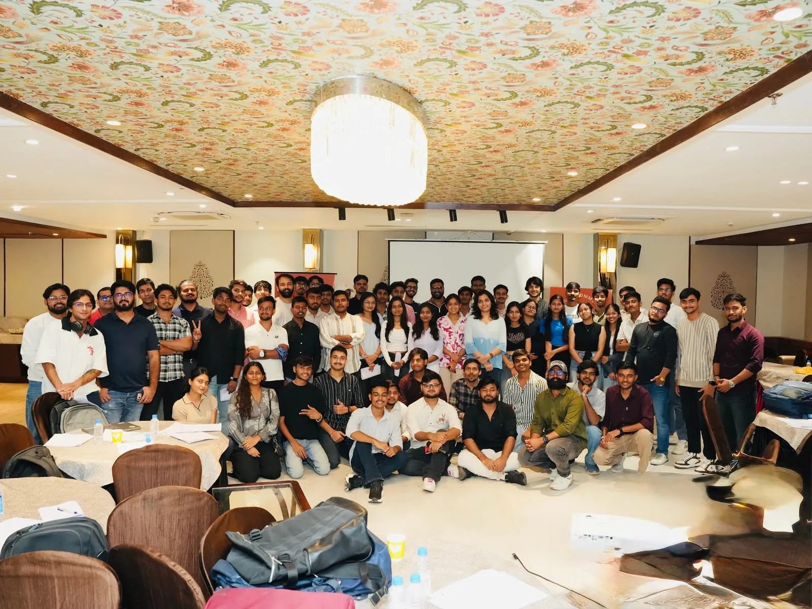 Attendees of the Claude Conversation posing for a group photo in a banquet hall under a chandelier