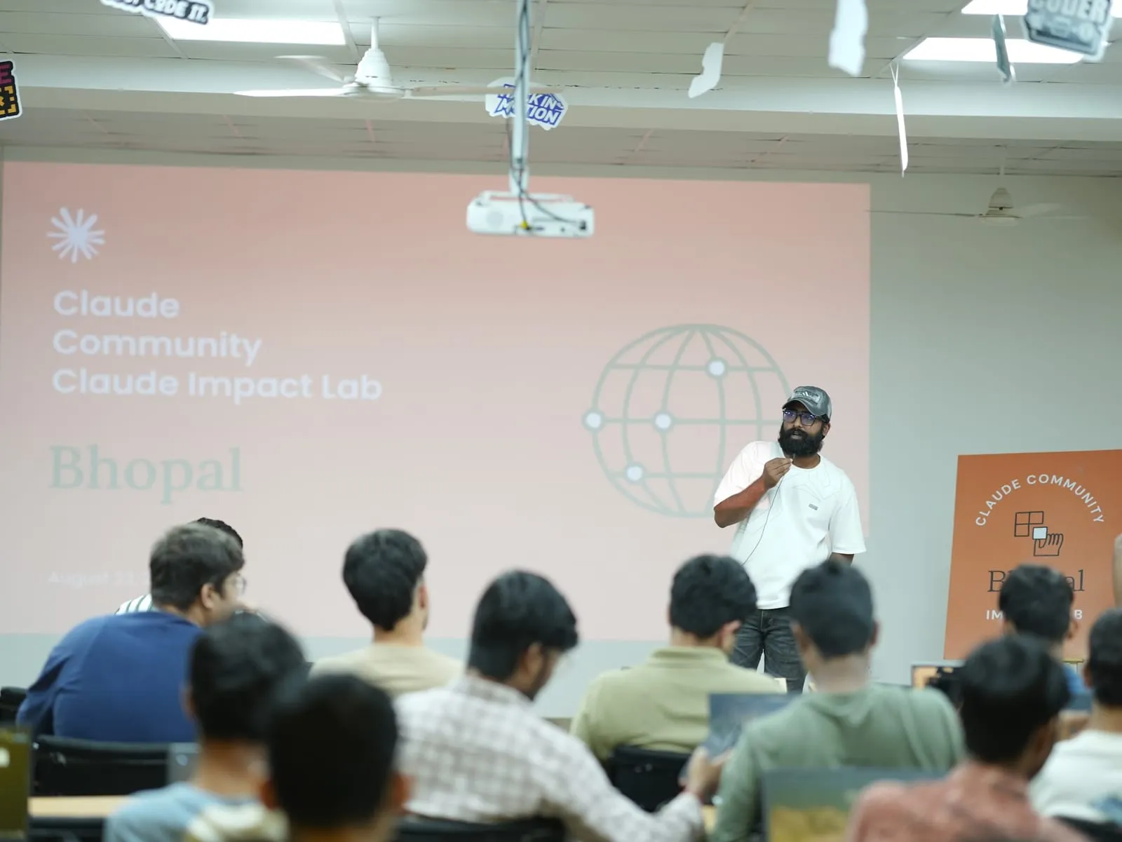 The host presenting in front of the Claude Community Claude Impact Lab Bhopal slide to a room of participants