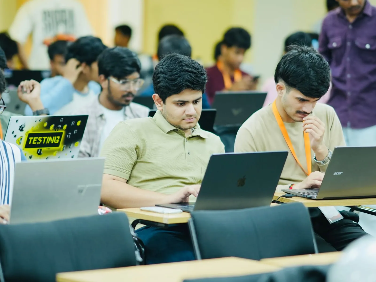 Two builders in orange lanyards concentrating on their laptops
