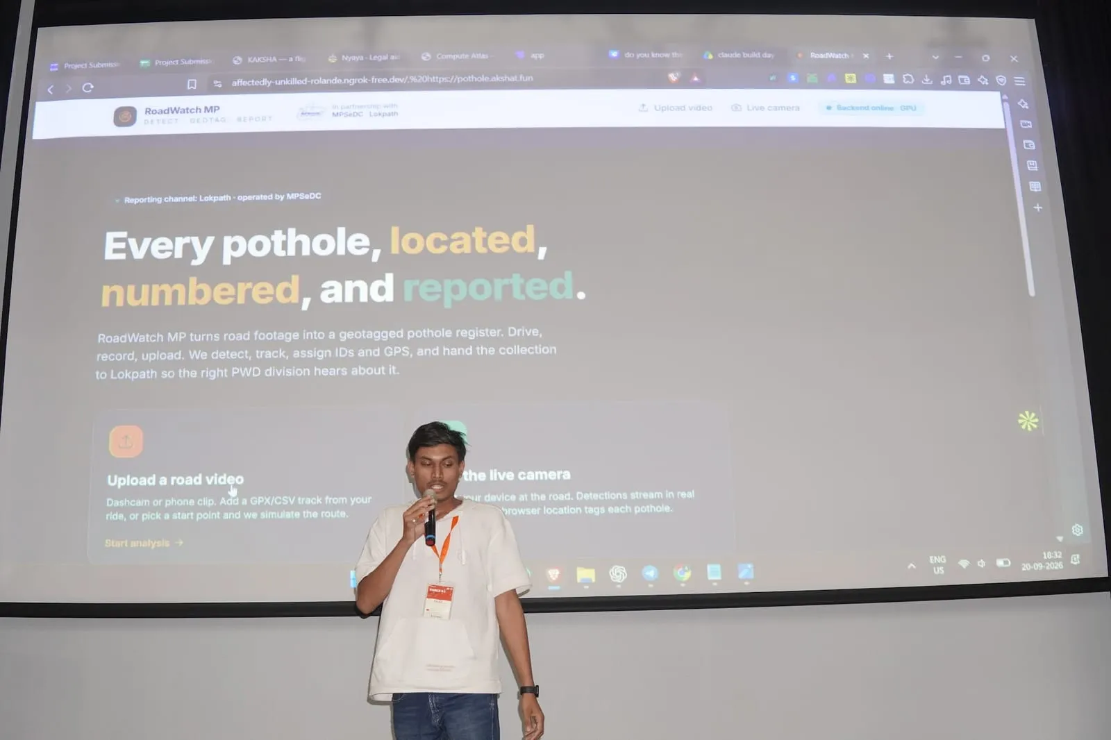 A builder demoing RoadWatch MP, a pothole-reporting app, on the auditorium screen