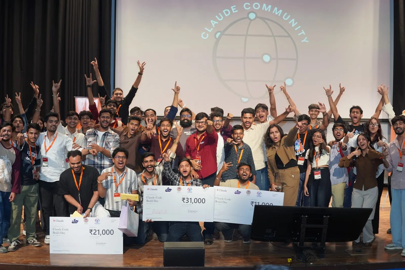 Winners and participants cheering on stage with the prize cheques, under the Claude Community globe