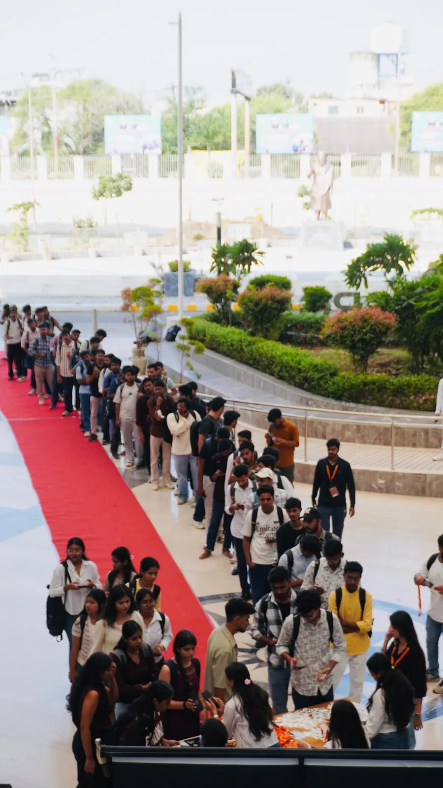 Participants queuing along a red carpet to the registration desk on arrival