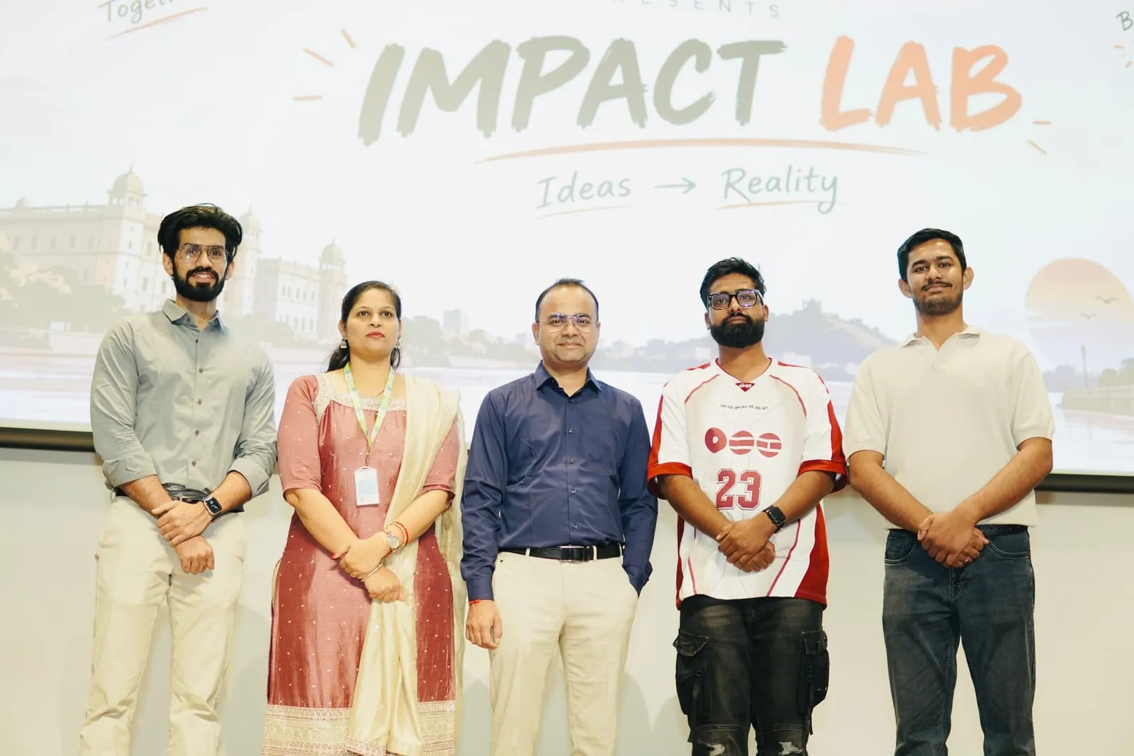Five people standing in front of the Impact Lab, Ideas to Reality slide